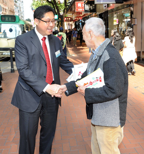 民政事务总署助理署长郭伟勋（左）向途人派发纪念品，宣传有效大厦管理及防火信息。